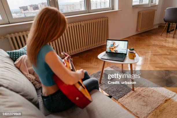 woman watching tutorial on laptop and playing guitar - misses vlog stock pictures, royalty-free photos & images