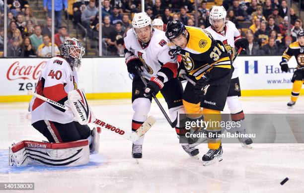 Patrice Bergeron of the Boston Bruins watches the loose puck against Milan Michalek of the Ottawa Senators at the TD Garden on February 28, 2012 in...