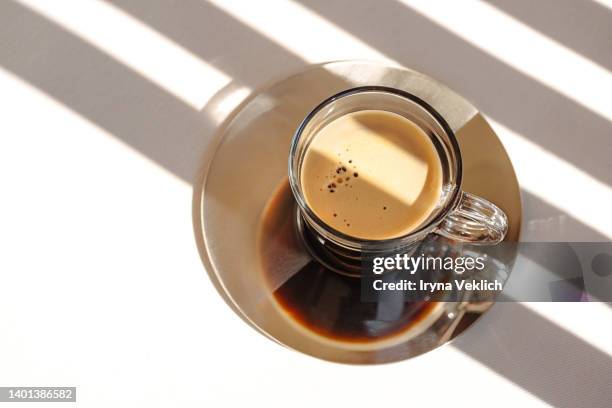 aromatic morning coffee in a glass cup and lines of shadows on white color background. - espressomaschine stock-fotos und bilder