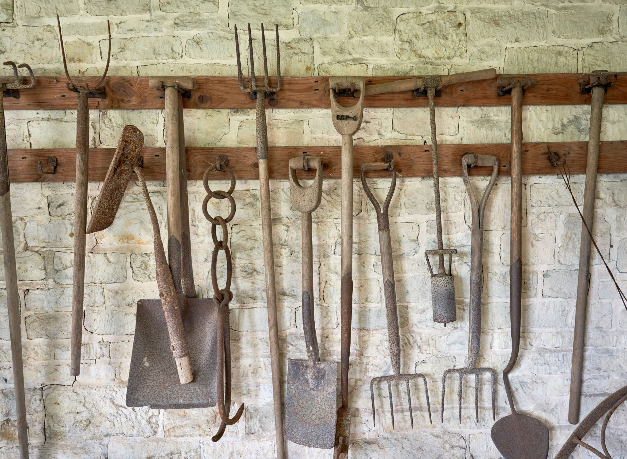 Vintage garden tools hanging on a whitewashed wall Vintage garden tools hanging on a whitewashed wall