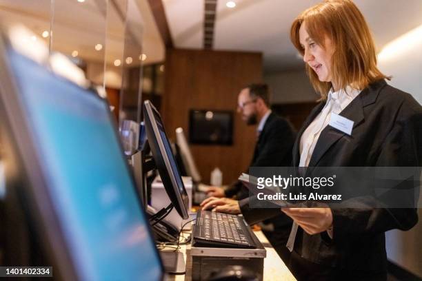 hotel concierges working at their desk - hotel staff stock pictures, royalty-free photos & images