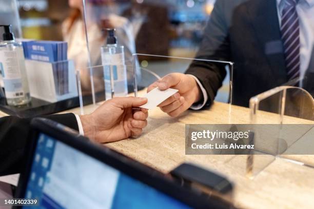 close-up of receptionist giving key card to a guest at reception desk - hotel key stock-fotos und bilder