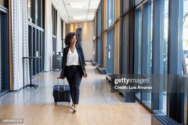 african businesswoman walking in hotel corridor with luggage - businesswoman hotel stock pictures, royalty-free photos & images