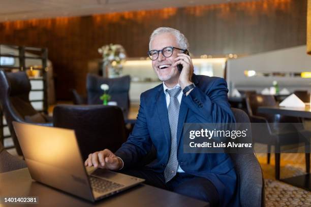 mature businessman talking on mobile phone while waiting in hotel lobby - lounge chair bildbanksfoton och bilder