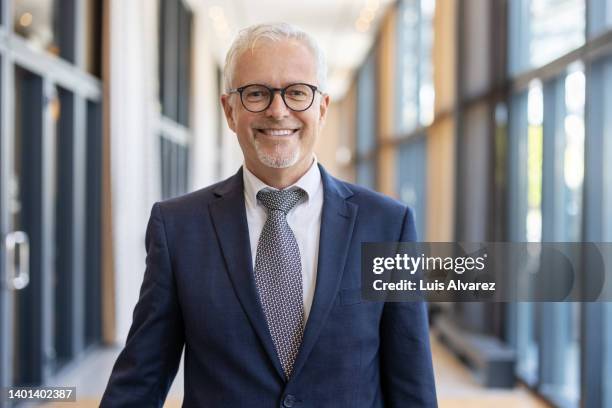 portrait of a mature businessman standing in hotel corridor - traje completo fotografías e imágenes de stock