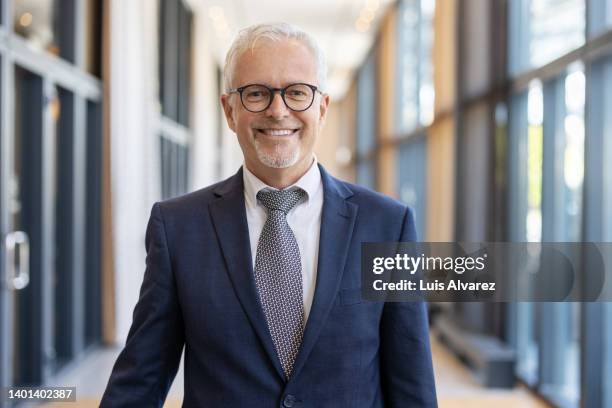 portrait of a mature businessman standing in hotel corridor - ceo portrait stock pictures, royalty-free photos & images