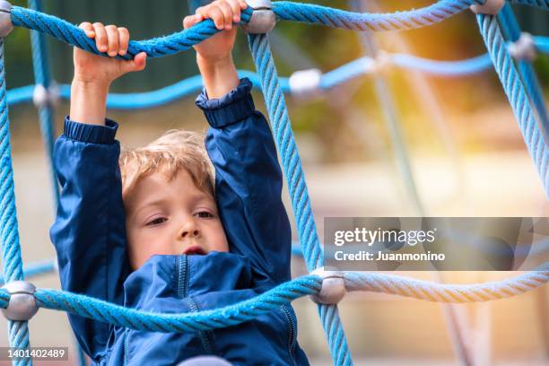 little boy hanging from robes at a schoolyard playground - asperger syndrome stock pictures, royalty-free photos & images