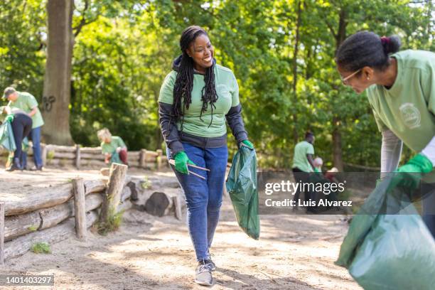 african woman talking with a female while collecting trash in nature - arab community life stock-fotos und bilder