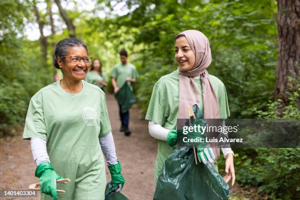 women working as volunteers in saving the environment from garbage - arab woman walking stockfoto's en -beelden