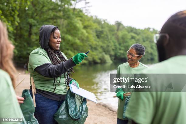 woman volunteer coordinator speaks to the group - reinigungsfahrzeug stock-fotos und bilder