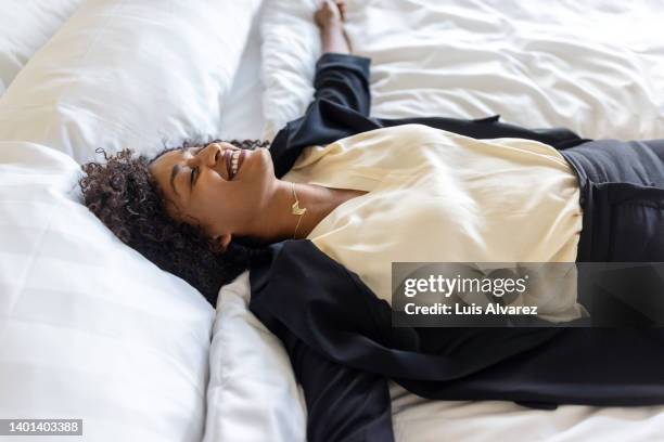 exhausted businesswoman lying on hotel room bed - locker room stock-fotos und bilder