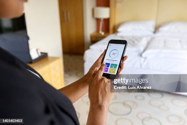 close-up view of a woman adjusting her hotel room air conditioner with a smart phone app - bedroom suite stock-fotos und bilder