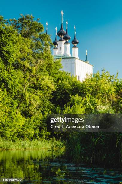 summer landscape in suzdal. the cathedral bell tower is reflected in the kamenka river against the background of green trees and grass. russia, vladimir region, golden ring of russia - suzdal stock pictures, royalty-free photos & images