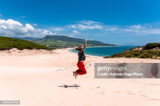 woman jumping in a beautiful beach and mountain landscape. - andalucia stock pictures, royalty-free photos & images