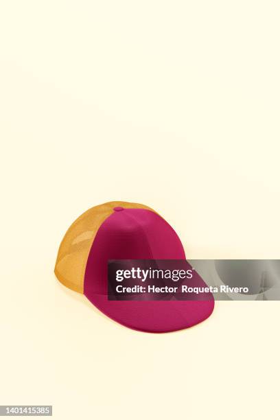 close-up of one orange and red cap against yellow background - baseball cap stock pictures, royalty-free photos & images