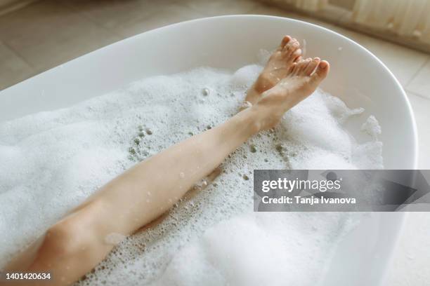 woman's feet in bubble bath - woman bath bubbles stock-fotos und bilder