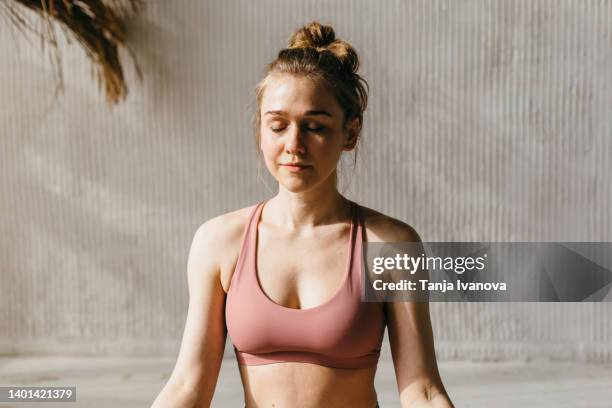 young woman meditates with her eyes closed close-up - young woman close at home stock pictures, royalty-free photos & images