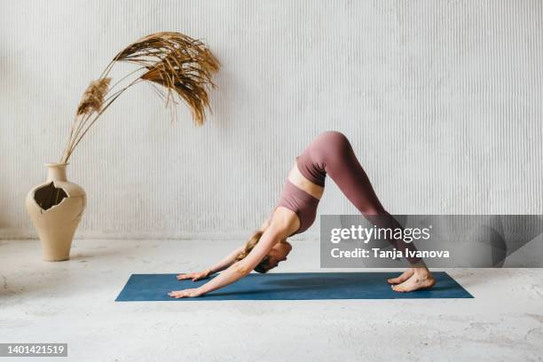 young woman practicing yoga in yoga class on exercise mat. adho mukha shvanasana  dog pose. - downward facing dog position stock pictures, royalty-free photos & images