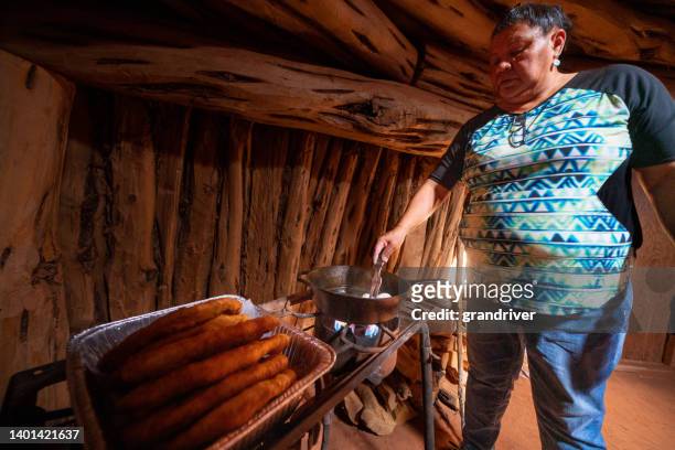 two women in their family hogan cooking up  some fry bread to make navajo tacos for their family - navajo hogan stockfoto's en -beelden