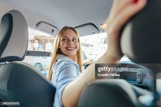 confident young woman driving car - reverse stockfoto's en -beelden