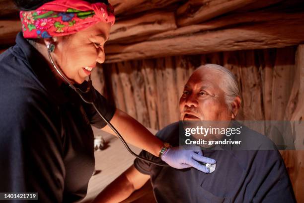 female paramedic emergency medical technician listens to her patient's heart and lungs, as she makes rounds to patients  who are homebound to make sure they are doing okay healthwise - indigenous american culture bildbanksfoton och bilder