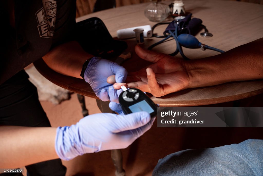 Paramedic Emergency Medical Technician Checks A Patient's Blood Glucose Levels With A Finger Poke And A Spot Of Blood She Uses A Glucometer
