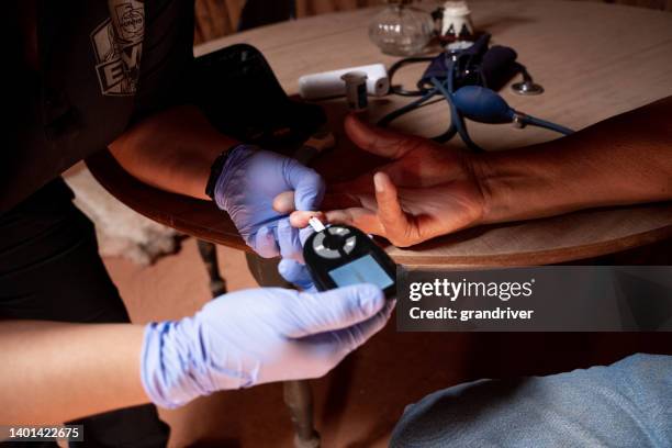 paramedic emergency medical technician checks a patient's blood glucose levels with a finger poke and a spot of blood she uses a glucometer - traditional native american medicine stock pictures, royalty-free photos & images