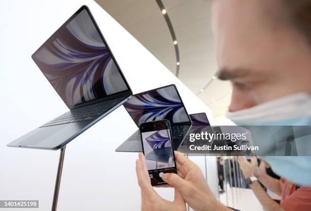 An attendee takes a picture of a newly redesigned MacBook Air laptop displayed during the WWDC22 at Apple Park on June 06, 2022 in Cupertino,...