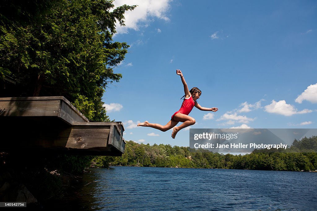 Young girl jumping off high dock