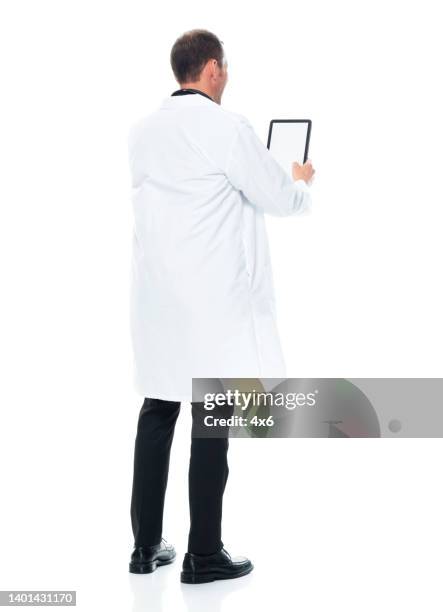 médico homem jovem caucasiano em frente ao fundo branco usando jaleco e usando tablet digital - male bum - fotografias e filmes do acervo