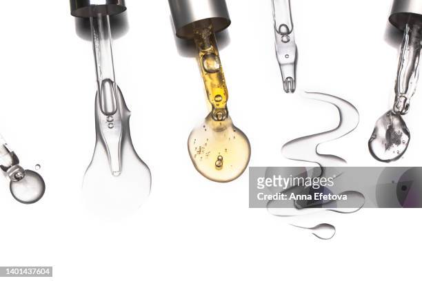 many glass pipettes spilling drops of different moisturizing lotions on white background. polyglutamic acid is new hyaluronic acid. macro photography - organic chemistry in laboratory fotografías e imágenes de stock