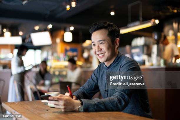 happy asian businessman using smart phone at café taiwan - man with iphone stock pictures, royalty-free photos & images