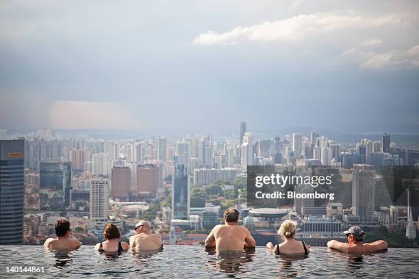 Hotel guests in the infinity pool at the SkyPark atop Marina Bay Sands look out towards the city skyline in Singapore, on Tuesday, Feb. 28, 2012. The...