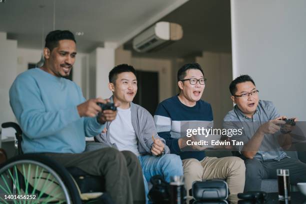 group asian friends play video games together at living room sitting on sofa - game four stockfoto's en -beelden