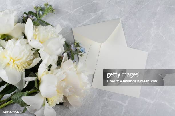 minimal styled flat lay with cream peony flower and empty blank card with envelope. mock up concept. top view, flat lay - white flower paper stock-fotos und bilder