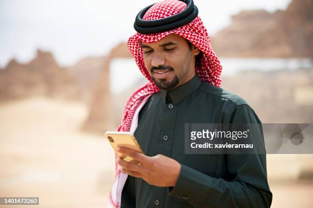 late 20s saudi man using phone in desert - saudi telecom stock pictures, royalty-free photos & images