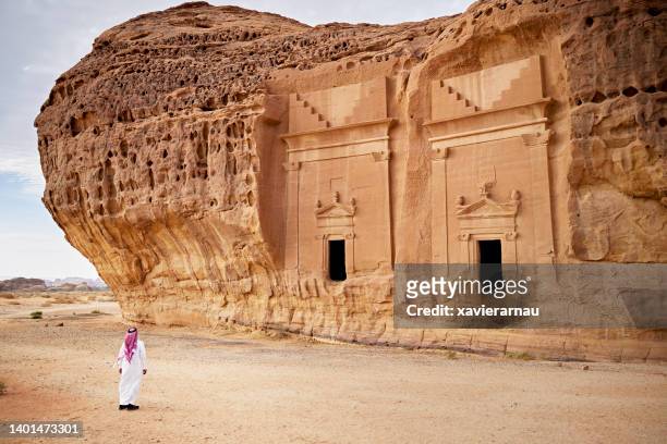 saudi man admiring ancient rock-cut architecture at hegra - mada'in saleh stockfoto's en -beelden