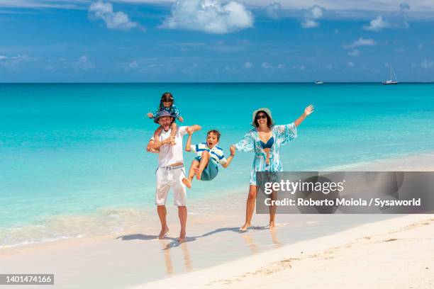 parents enjoying swinging and piggyback two little sons on a beach - caribe fotografías e imágenes de stock