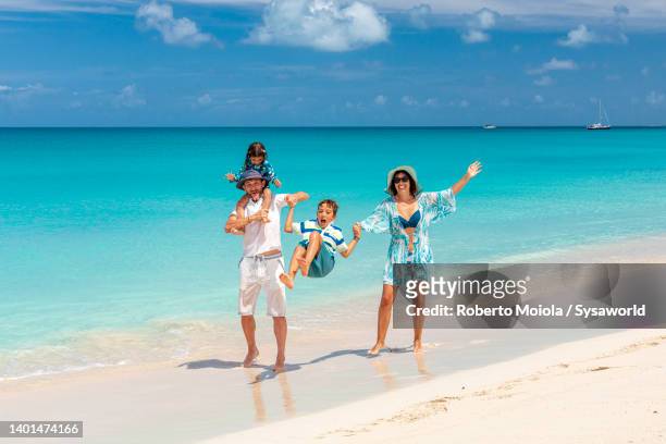 parents enjoying swinging and piggyback two little sons on a beach - caraïbische zee stockfoto's en -beelden