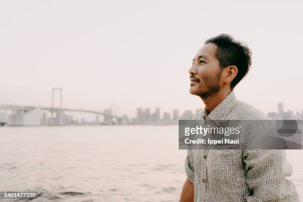 man contemplating by sea side at sunset, tokyo bay - portrait waist up stock pictures, royalty-free photos & images