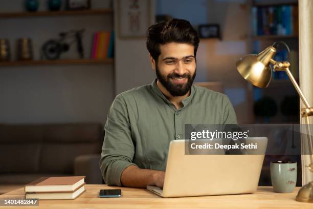 handsome young man in working on laptop stock photo - indian man stockfoto's en -beelden