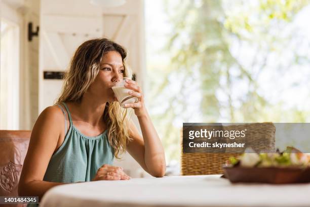 donna rilassata che beve latte al tavolo da pranzo. - drink milk foto e immagini stock