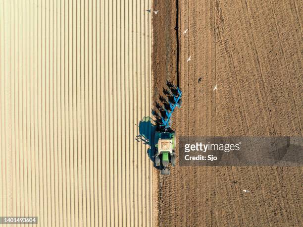 traktor, der den boden für den anbau von pflanzen von oben vorbereitet - harrow stock-fotos und bilder