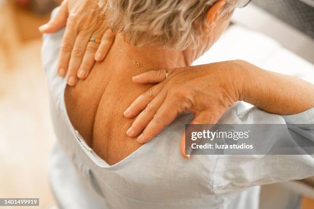 senior woman massaging the pain in her neck - woman's neck stock pictures, royalty-free photos & images