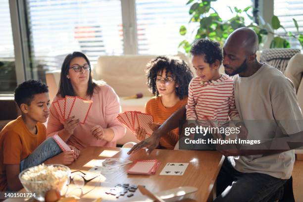 happy multiracial family with three children playing card at home. - board games stock pictures, royalty-free photos & images
