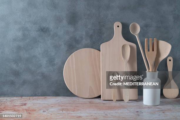 moderne küchenutensilien in heller holzfarbe mit schöpfkelle, schneidebrettern und kochgeschirr auf grau - kitchen bench wood stock-fotos und bilder