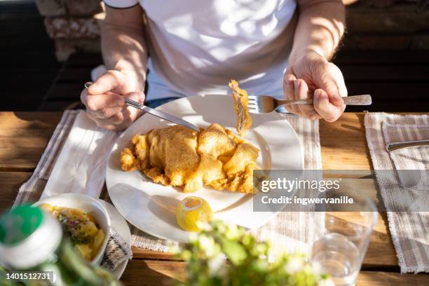 man eating schnitzel with potatoes in a restaurant on sunny day outside - schnitzel stock-fotos und bilder