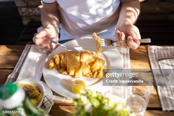 man eating schnitzel with potatoes in a restaurant on sunny day outside - costeleta comida imagens e fotografias de stock