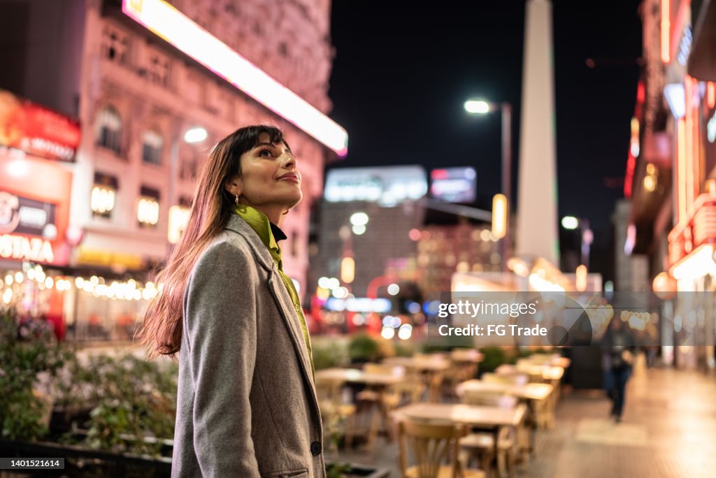 Young woman contemplating city lights at night