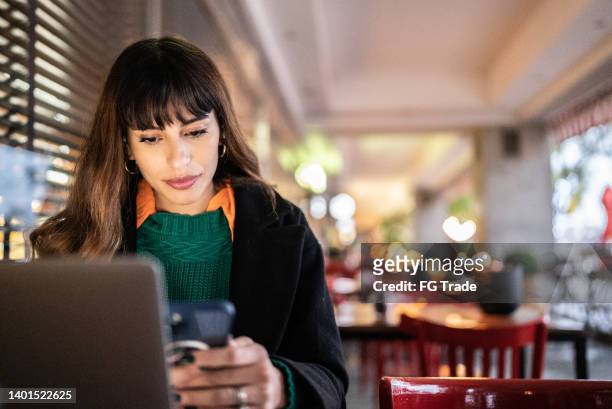 businesswoman working using smartphone in a restaurant - answering stockfoto's en -beelden